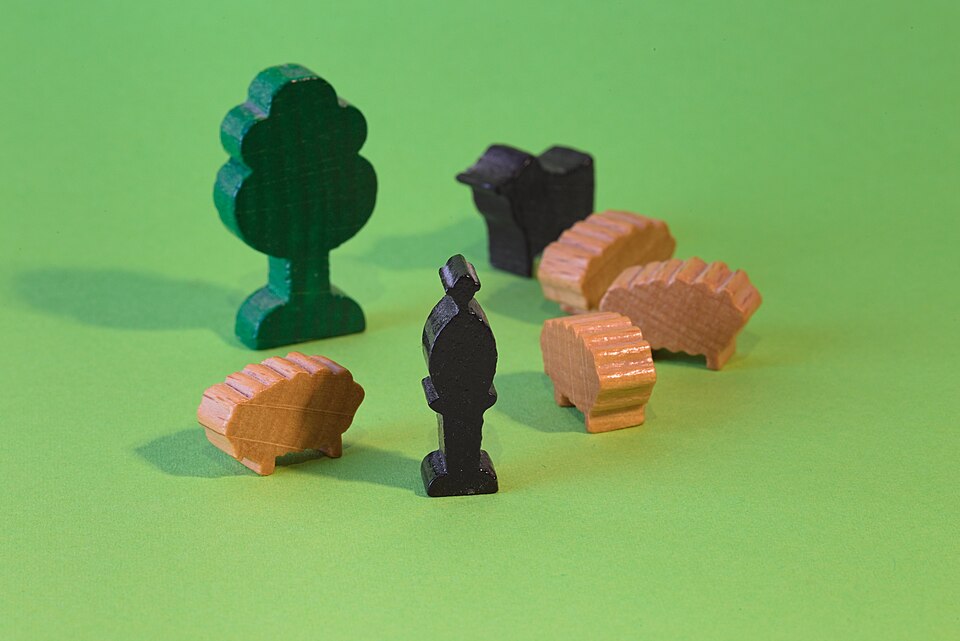 Small wooden toy figures of a shepherd, a flock of sheep, a dog, and a tree